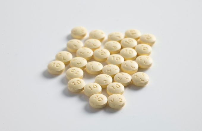 A small pile of cream coloured prescription pills on a plain white surface