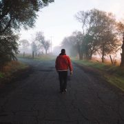 Young adult walking alone down a road