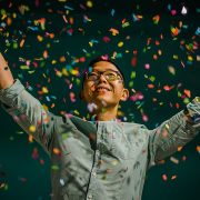 Boy holding up arms in cascading ticker tape