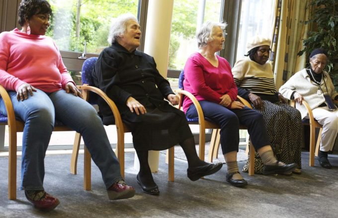 older people exercising in chairs in a care home setting