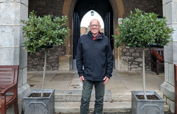 Malcolm standing smiling between two bay trees