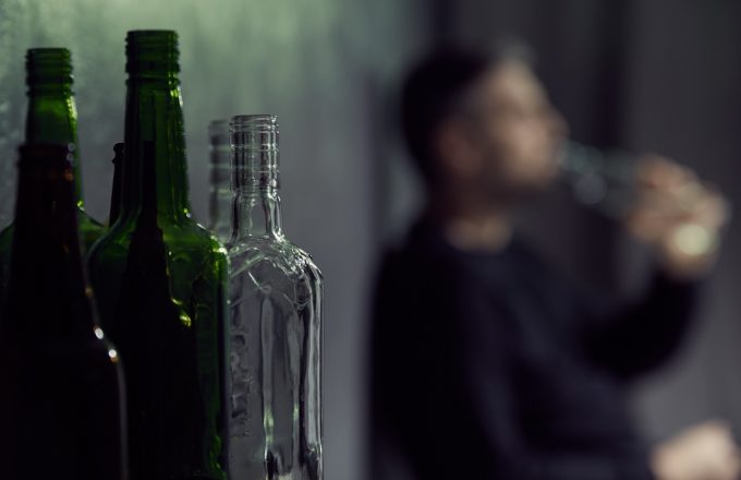 Empty bottles of alcohol with drinking man