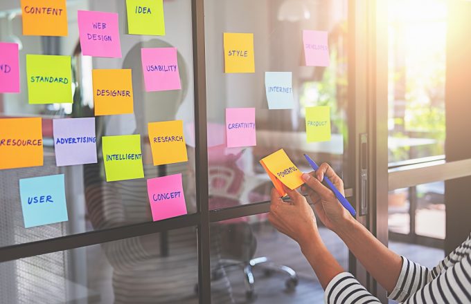 Student sticks sticky notes to office wall to help think creatively about research