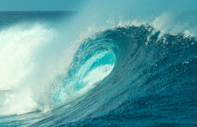 CLOSE UP: Foaming ocean water splashes high in the sky near big barrel wave.