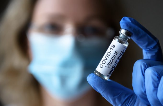 COVID-19 vaccine in researcher hand close-up, female doctor and bottle with medication for coronavirus cure in lab. Concept of corona virus treatment and clinical trial during coronavirus pandemic.