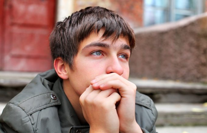 adolescent male sits on steps looking pensive