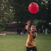 children playing with red balloon in park
