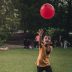 children playing with red balloon in park