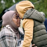 Happy middle-eastern mother in headscarf touching foreheads with daughter while finding her after escape from battlefield
