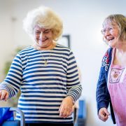 Two older women laugh together in a shared space