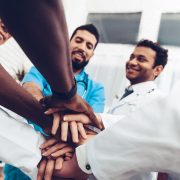 Professional Doctors Holding Each Other Hands. Multinational Medician Meeting. Teamwork Connection. Clinician Team Group. Working Together. Office Friendship. Partnership Arms Shaking.