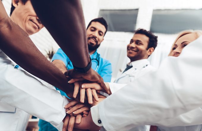 Professional Doctors Holding Each Other Hands. Multinational Medician Meeting. Teamwork Connection. Clinician Team Group. Working Together. Office Friendship. Partnership Arms Shaking.