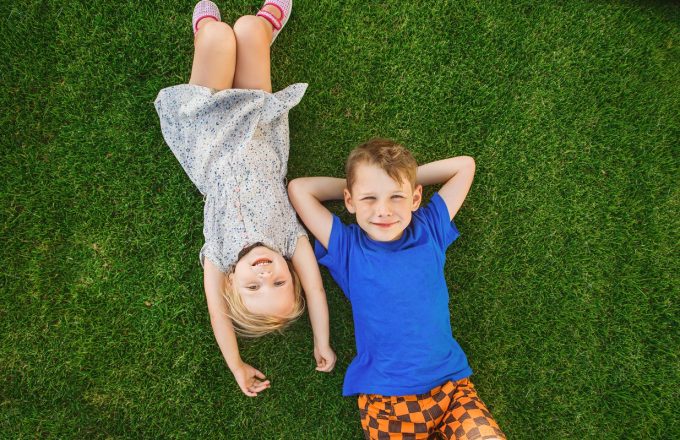 children lying on the green grass in the Park.