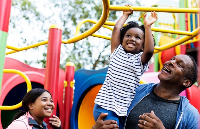 A fyoung family play on brightly coloured outdoor play equipment