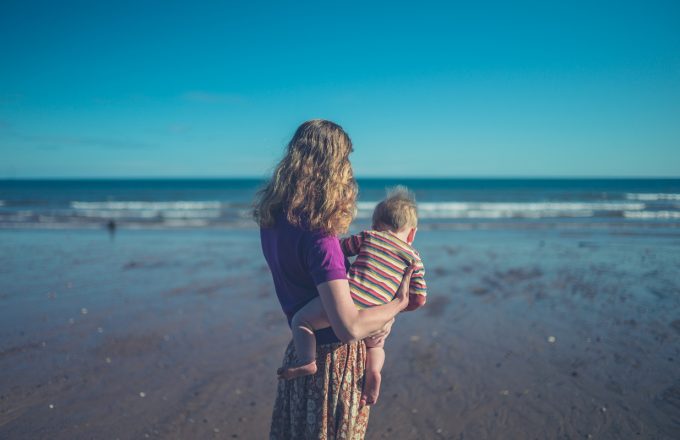 Mother on beach holding her baby boy