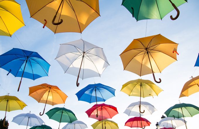 Multi-coloured umbrellas floating in a blue sky