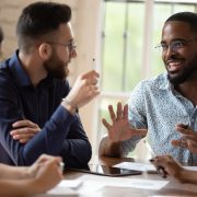 Motivated engaged young african american male sharing ideas with a diverse team around a table.