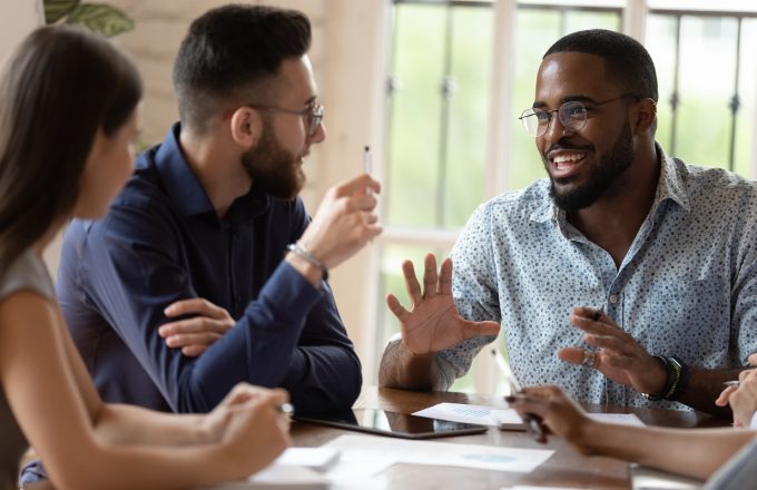 Motivated engaged young african american male sharing ideas with a diverse team around a table.
