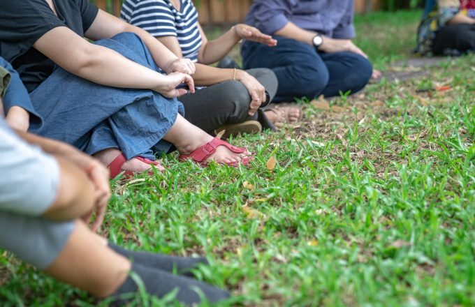 People sitting on grass in a semicircle talking