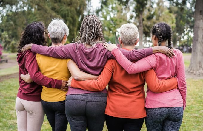 Back view of multi generational women having fun together outdoors in city park -