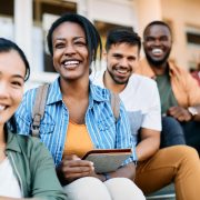 Multi-ethnic group of happy college students enjoy outdoors and look at camera.