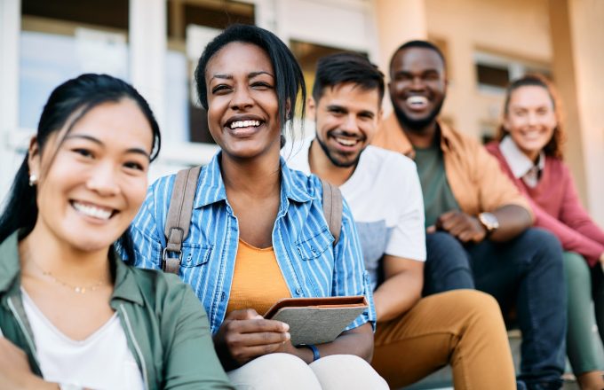 Multi-ethnic group of happy college students enjoy outdoors and look at camera.