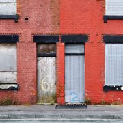 Boarded up terraced houses in the UK with red paintwork.