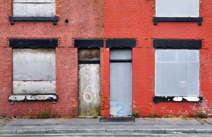 Boarded up terraced houses in the UK with red paintwork.