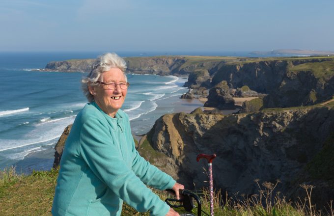 Happy elderly female pensioner by coast scene Cornwall England UK