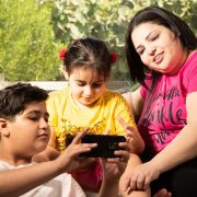 Family sitting on sofa smiling and looking at phone