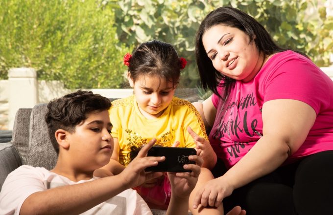Family sitting on sofa smiling and looking at phone