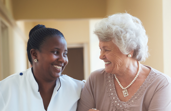 Smiling home caregiver and senior woman walking together