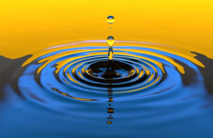 A water droplet splashing into water causing ripples.