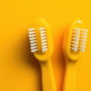Modern yellow kids toothbrushes on a yellow background. Generative AI.