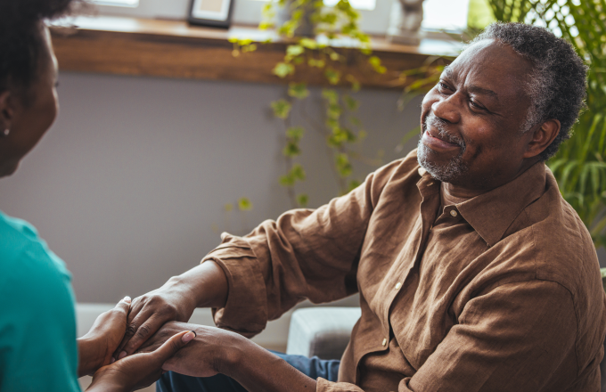 Female carer holding hands of senior man