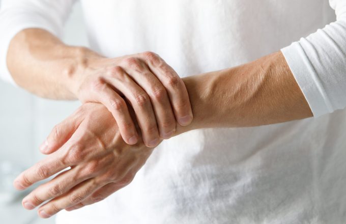 An adult person wearing a white t-shirt holding a painful wrist