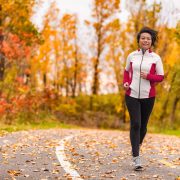 Mature Asian woman running active in her 50s. Middle aged female jogging outdoor living healthy lifestyle in beautiful autumn city park in colorful fall foliage. Asian Chinese adult in her fifties.