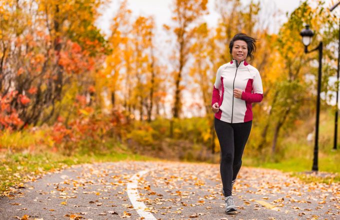 Mature Asian woman running active in her 50s. Middle aged female jogging outdoor living healthy lifestyle in beautiful autumn city park in colorful fall foliage. Asian Chinese adult in her fifties.