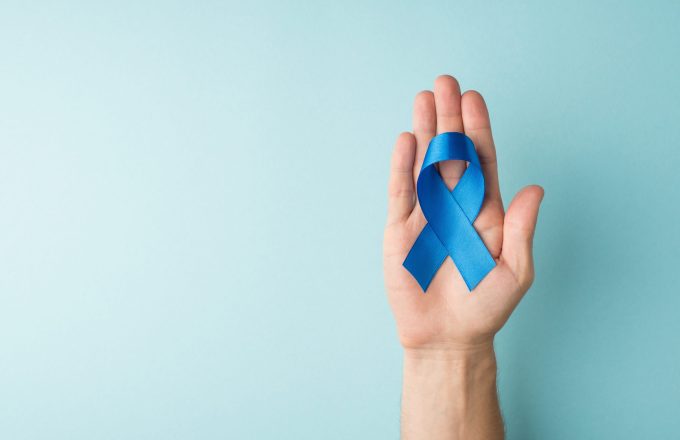 First person top view photo of male hand holding blue silk ribbon in palm symbol of prostate cancer awareness on isolated pastel blue background with blank space