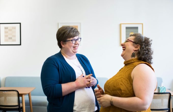 Two women standing and looking at each other whilst laughing