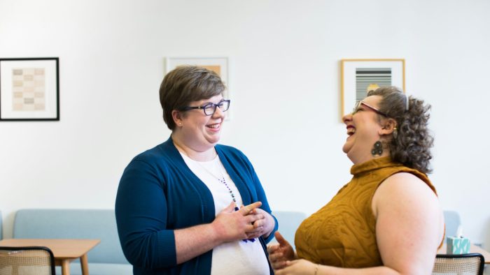 Two women standing and looking at each other whilst laughing