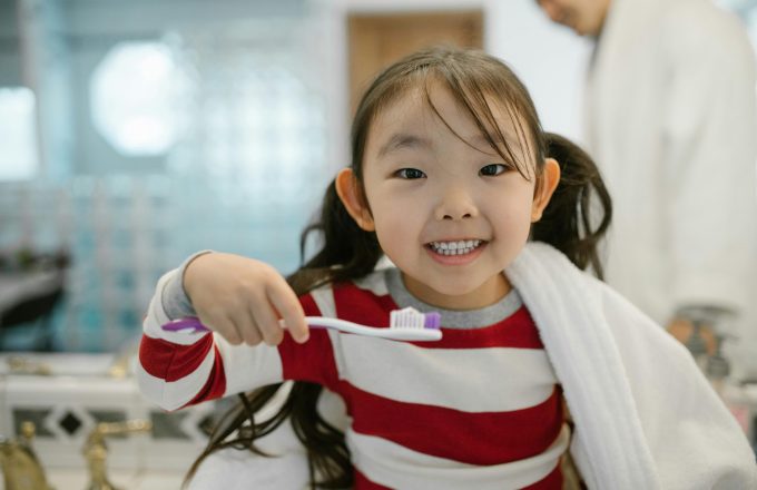 Young girl smiling and holding toothbrush