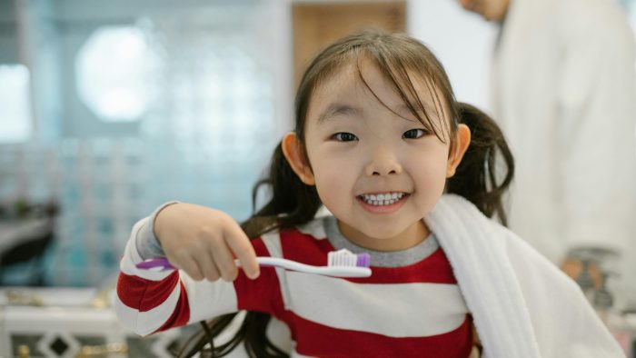 Young girl smiling and holding toothbrush